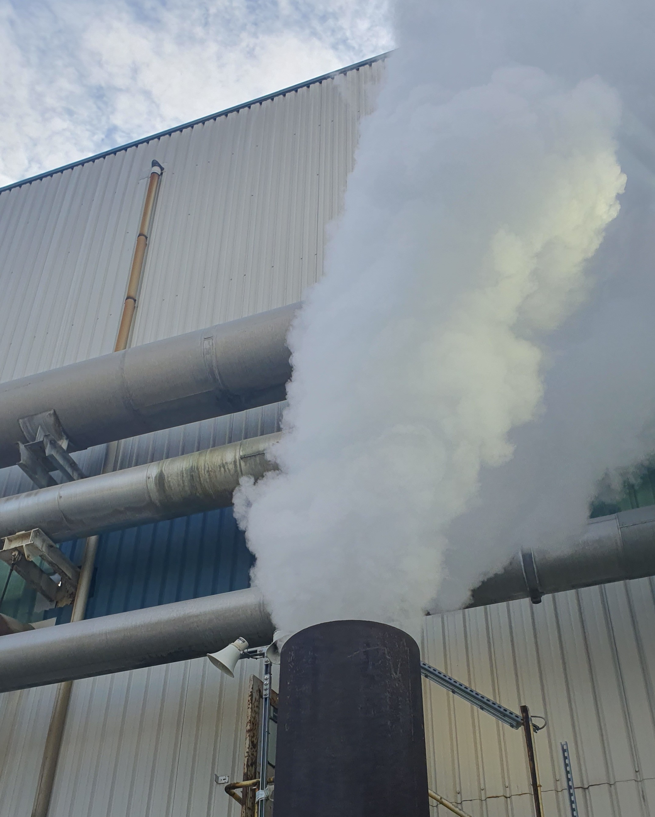 Panache de vapeur rejeté sur un site industriel illustrant un gisement potentiel de chaleur fatale à qualifier.